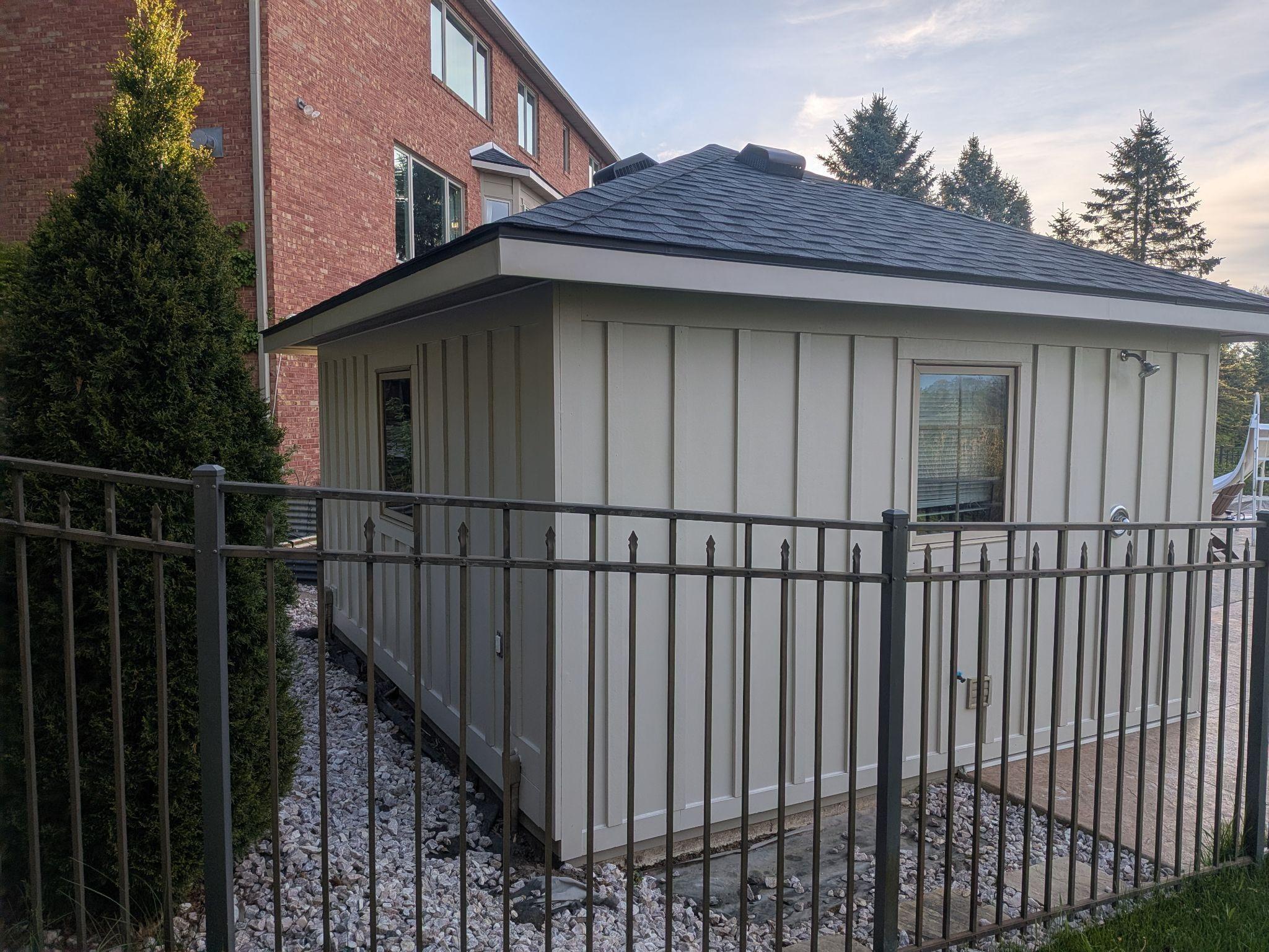 The same pool house re-sided in cream board-and-batten with new black fascia and trim